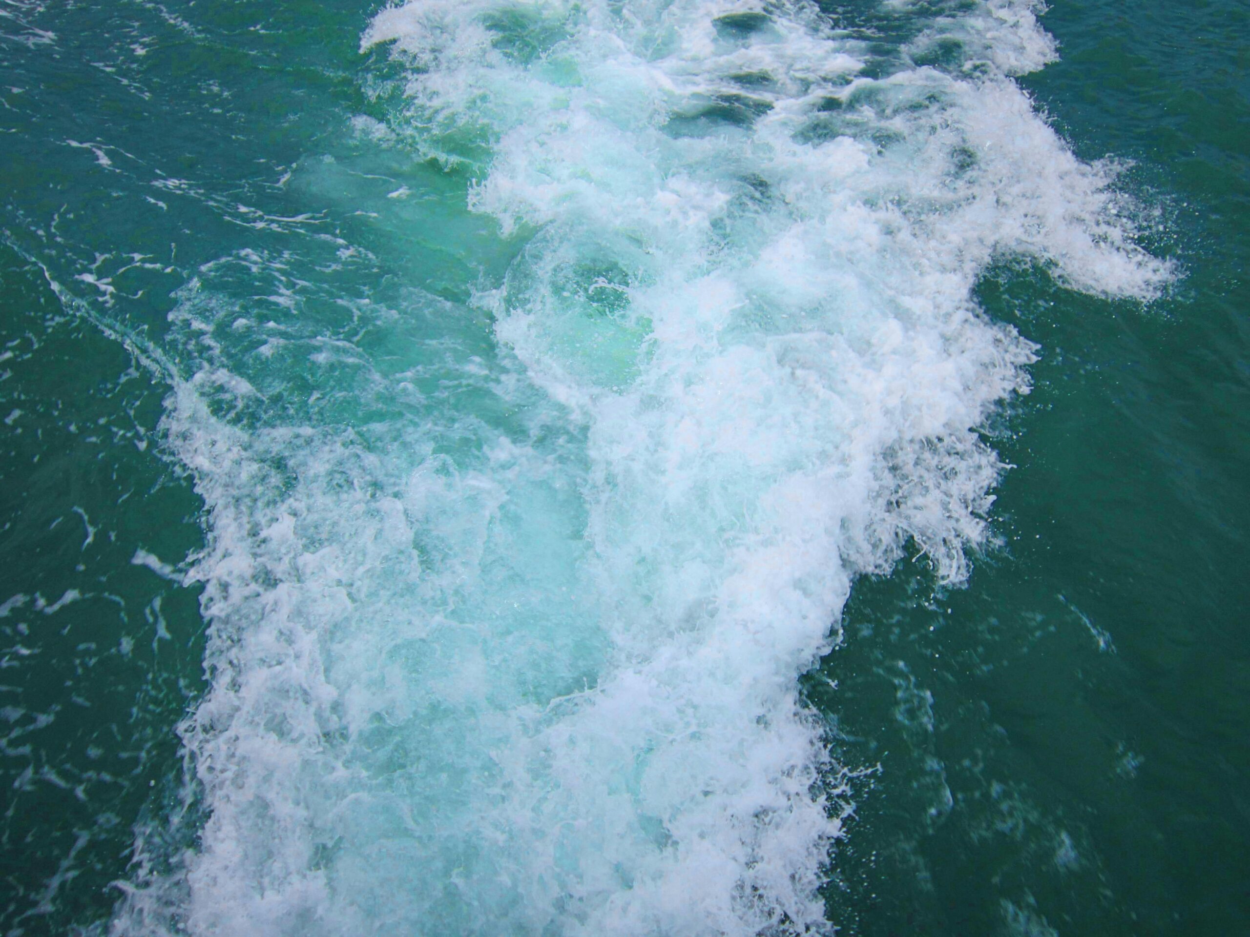 Aerial view of turquoise ocean waves crashing with white foam on the surface.